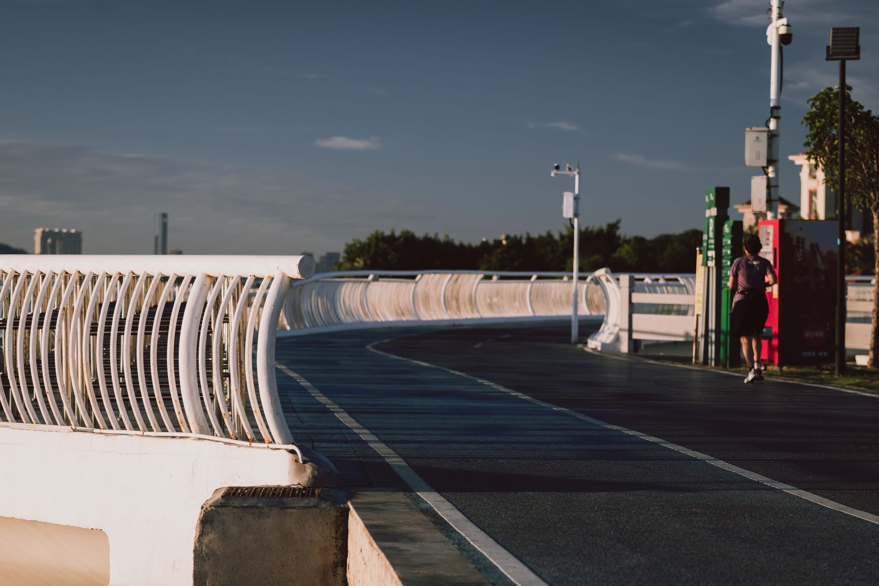 Lone runner jogging along a modern curved bridge in morning light