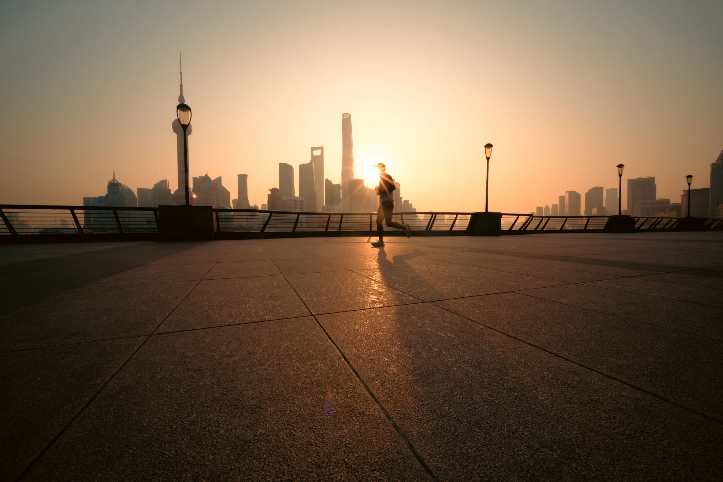 Runner silhouetted against the sunrise over the city skyline