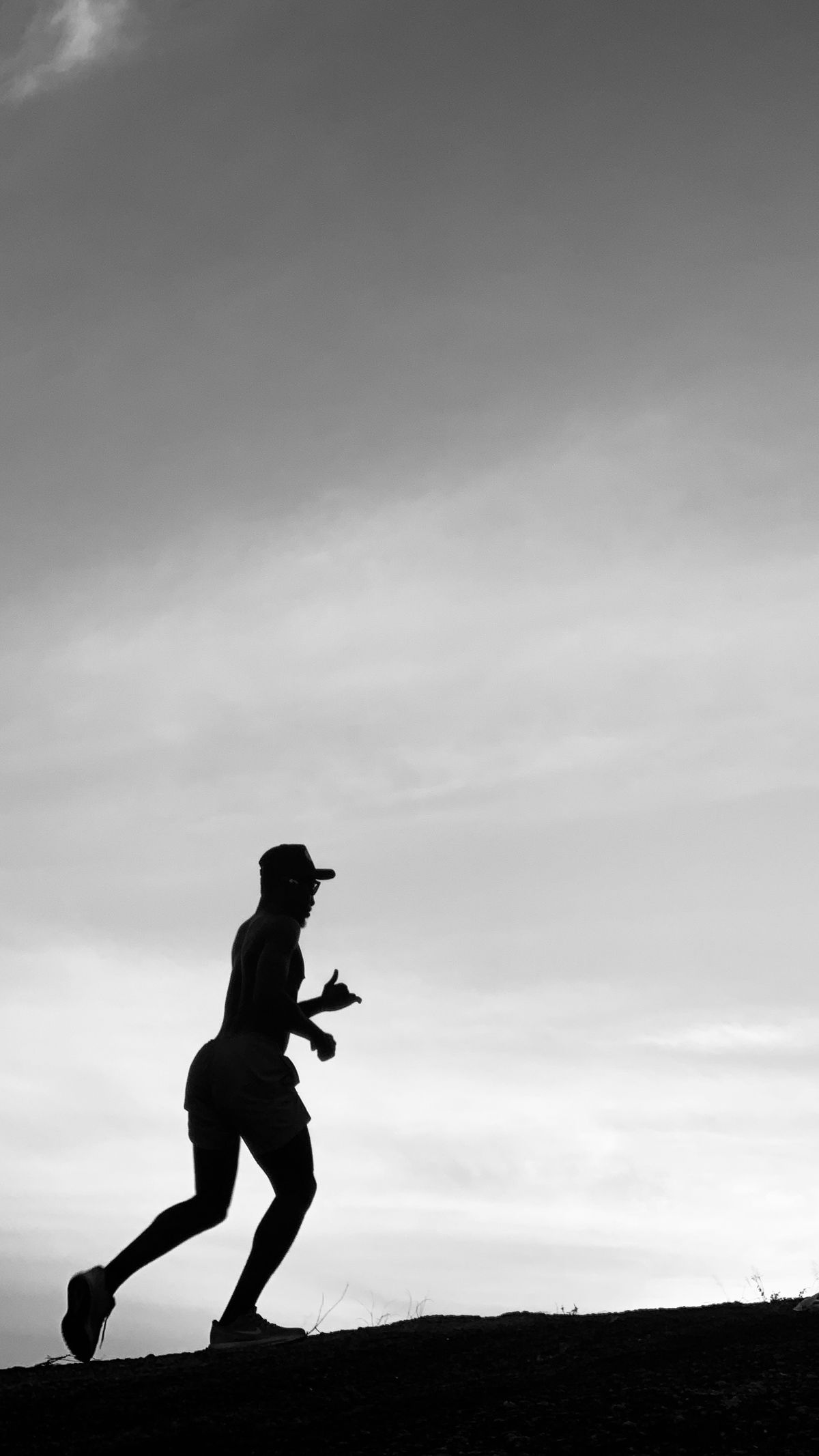 Silhouette of a man running uphill during twilight